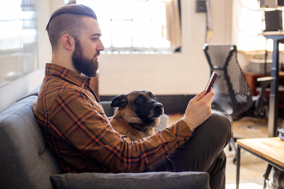 Junger Mann schaut zu Hause auf dem Sofa auf sein Smartphone