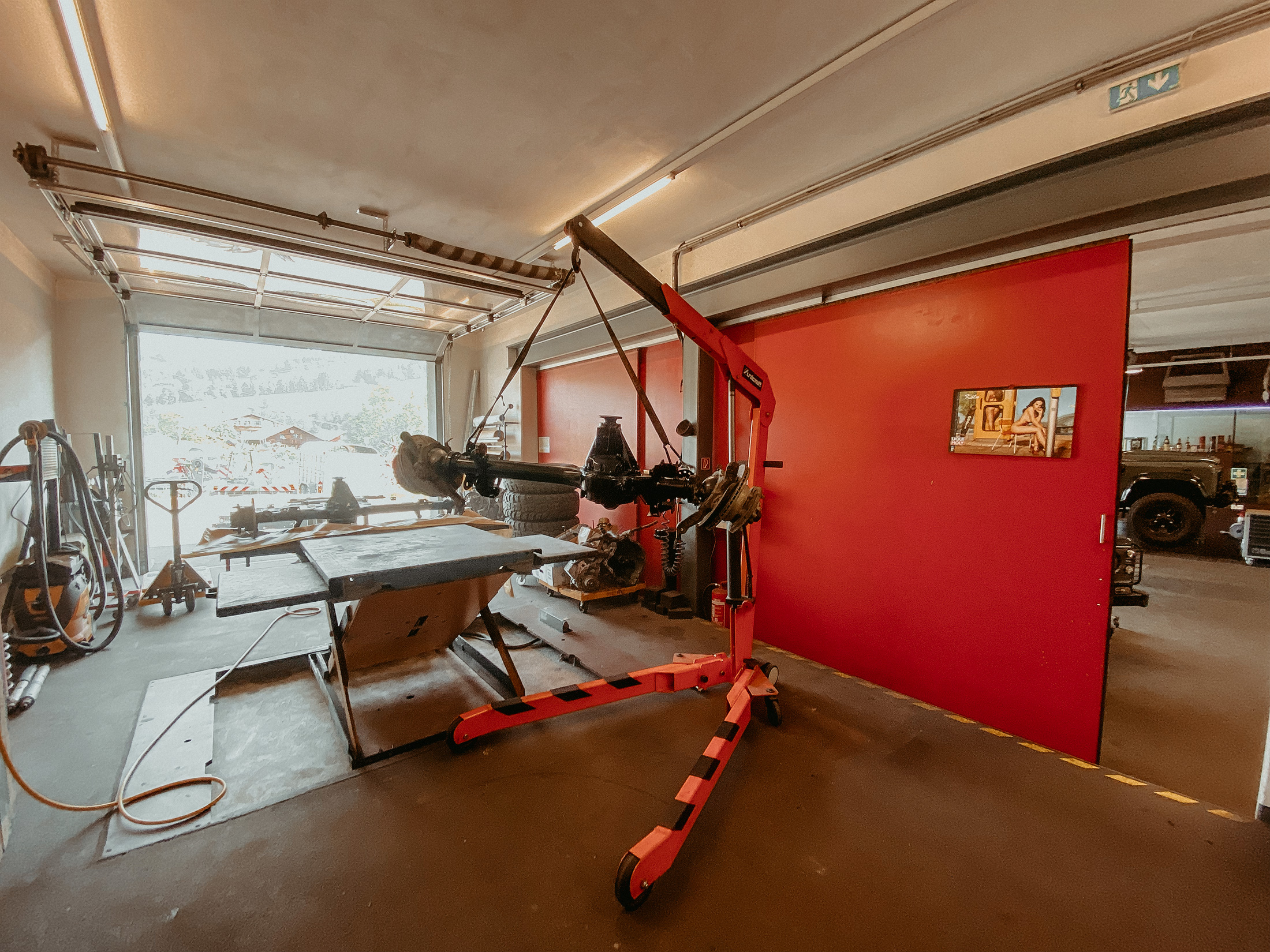 Blick in die Werkstatthalle mit Hebebühne und Defender